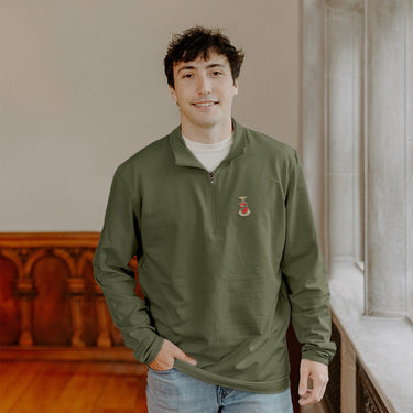 Male model wearing the pine Kappa Sigma Embroidered Luxe Quarter Zip in front of stained glass windows with fraternity crests.