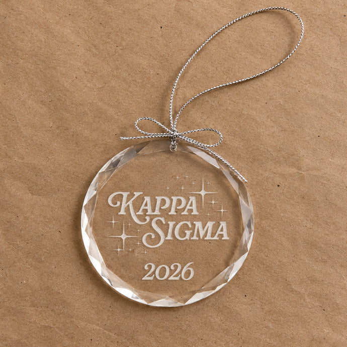 2026 Limited Edition clear glass holiday ornament featuring engraved fraternity design and silver hanging string