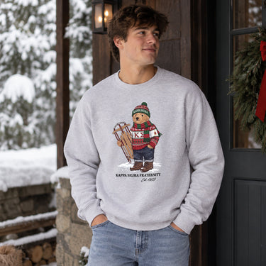 Man wearing a grey crewneck with festive fraternity bear design