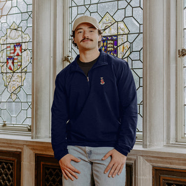 Male model wearing the navy-colored Kappa Sigma Embroidered Luxe Quarter Zip with crest embroidery, standing by a window in a formal setting.